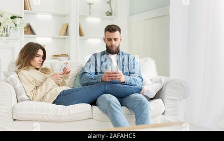 Internet addiction. Young couple using smartphones on sofa Stock Photo