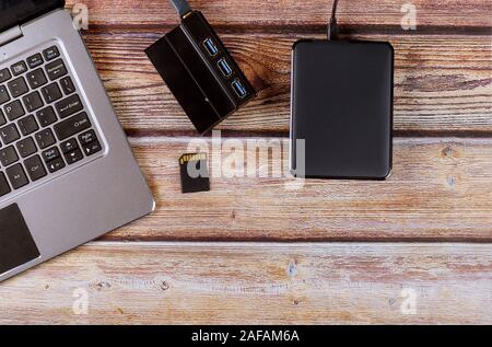 Photographers desktop workspace external backup disk hard drive connected to laptop computer transfer photos to SD cards Stock Photo