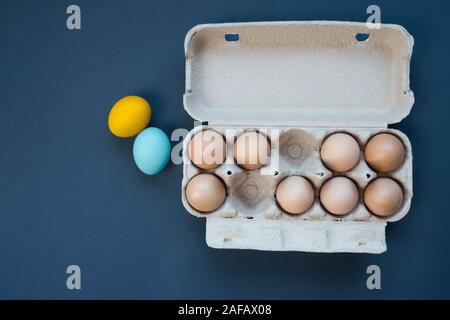 raw and colored eggs on blue background, Easter holidays decoration	of different eggs colors. Blue and yellow eggs Stock Photo