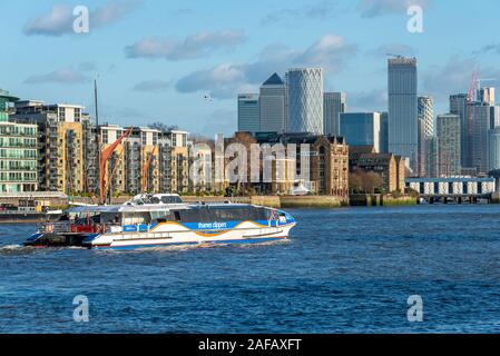 Thames Clippers riverbus on Wapping stretch of River Thames, London, UK with Canary Wharf skyscrapers skyline. Central Business District Isle of Dogs Stock Photo