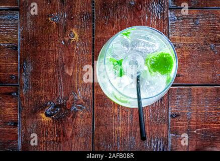 Top down view of a glass of mojito cocktail with lime and mint over ice cubes Stock Photo