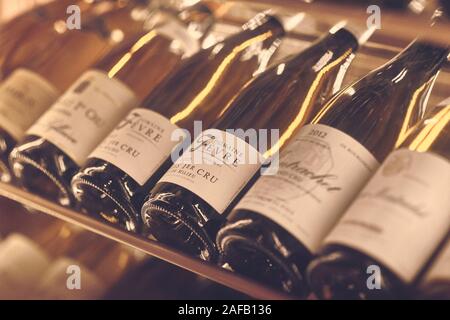 Paris, France - Dec 2019: Mood shot of white wine Domaine Fevre Chablis 1er Cru Fourchaume and other wines in rack in restaurant. Close up wine bottle Stock Photo