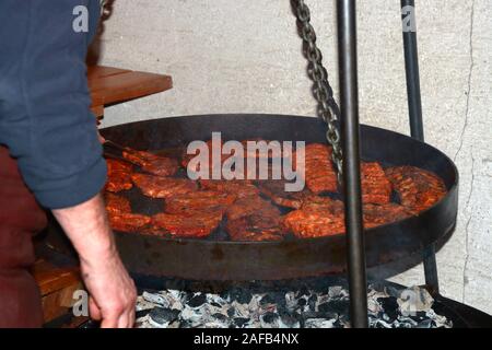 grill chef holding steel tongs and roasting steaks on big outdoor pan, grill master works on large pan and turns steaks Stock Photo