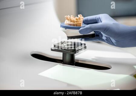 Dental technician placing jaw model into the 3d scanner at the laboratory, close-up Stock Photo