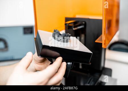 Dental technician removing jaw model from a 3d printer at the laboratory, modeling frame for implant production Stock Photo
