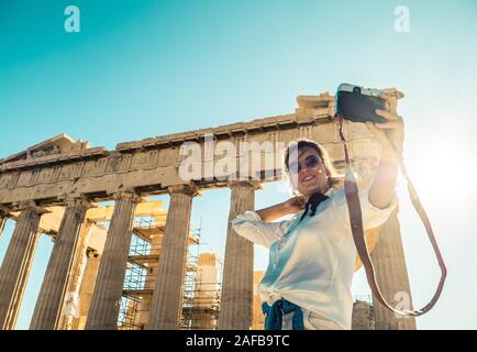 Young woman tourist taking pictures at parthenon in Athens acropolis, Greece Stock Photo