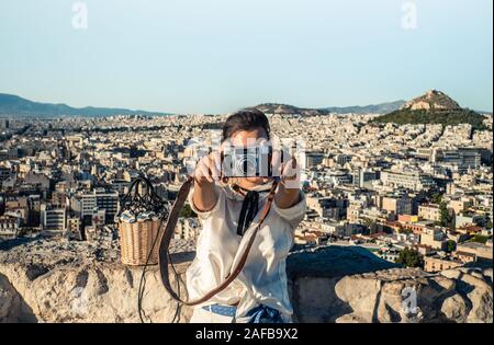 Young woman tourist taking pictures at parthenon in Athens acropolis, Greece Stock Photo