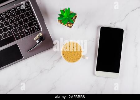 Mix of office supplies with smart phone gadgets wireless headphone working on a laptop computer in a cup of coffee view from above. Stock Photo