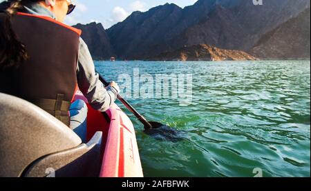 Woman kayaking in a scenic lake surrounded by mountains , active lifestyle Stock Photo