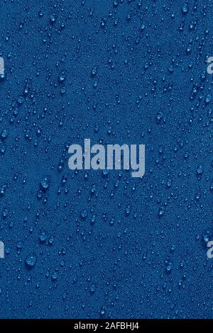 classic blue color waterproof hydrophobic flat cloth closeup with water drops background. Stock Photo