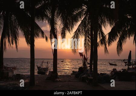 Sunset on the beach with coconut trees and fishing boat in tropical sea Stock Photo