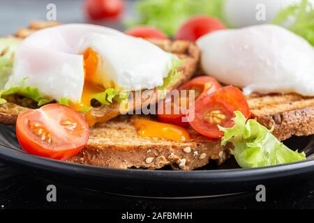Breakfast toasts and poached eggs, served with lettuce and tomatoes. Stock Photo
