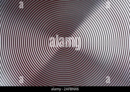 Hypnosis spiral. The alternation of red and light stripes. Aluminum disc. Enamel coating. Metallic shine. Stock Photo