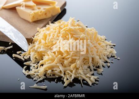 Grated cheese and a piece of cheese on a wooden board Stock Photo