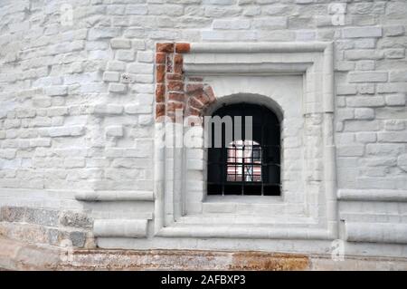 Window with bars in the old brick wall of the church. Russian architecture. Stock Photo