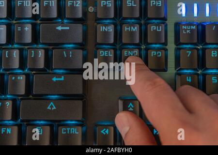 male finger presses the end key on the backlit keyboard Stock Photo