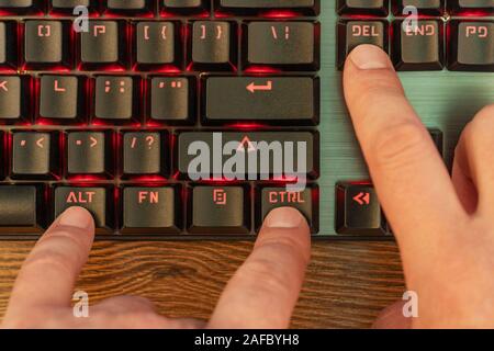 male hand presses three keys simultaneously on the black keyboard - control alt and delete Stock Photo