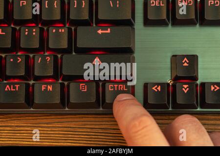 index finger of a male hand presses the control key on a black keyboard Stock Photo