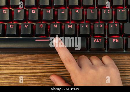 child index finger presses the spacebar on the black keyboard Stock Photo