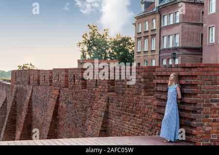 portrait of a lonely pensive woman leaning on an old brick wall of a castle Stock Photo