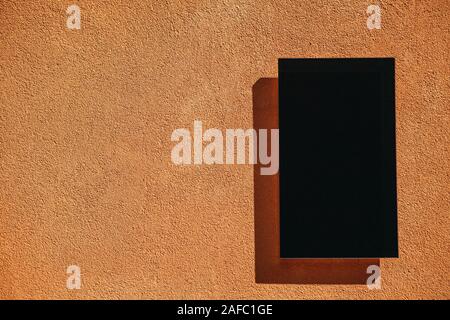 Empty black plate with copy space on orange wall background in minimal style. Stock Photo