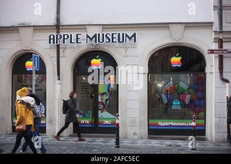 A female in black business clothing and backpack walking past the front of privately owned Apple Museum. Czech Republic. Stock Photo