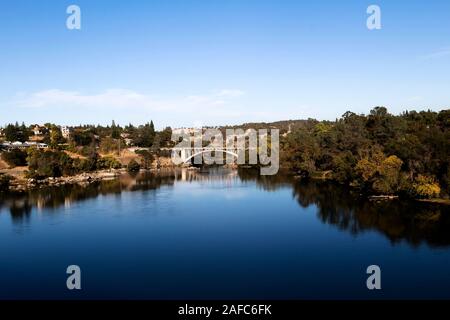 Blue Water And Sky Lake Natoma And Rainbow Bridge Folsom California With Trees Reflected In Water Stock Photo