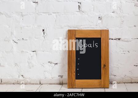 Board with new goals. Enter new goals. The inscription in chalk on a black chalkboard in a frame of wood. Stock Photo