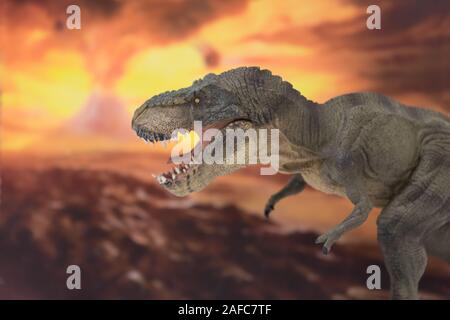 Portrait of walking and dangerous tyrannosaurus rex with erupting volcano in the background. Stock Photo