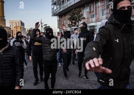 Residents of the Shia Bachoura neighbourhood marched through Downtown Beirut wearing balaclavas and shouting pro Shia chants. Some tried to stop photographers from taking their picture before tearing down protest banners, burning them in the road and attacking police and army personel with stones and fireworks on Saturday evening. Police responded with tear gas during a pitched battle lasting several hours. Beirut 14 Dec 2019 Stock Photo