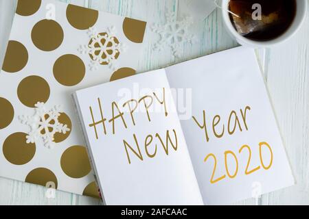 Sample layout of New Year's greetings with snowflakes, open notebook, cup of tea on a light wooden background. Frame for text greetings for Christmas Stock Photo