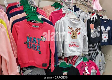 Large selection of children's clothing in the store. A new collection of fashionable clothes for children hangs in a boutique. Bright sweatshirts Chri Stock Photo