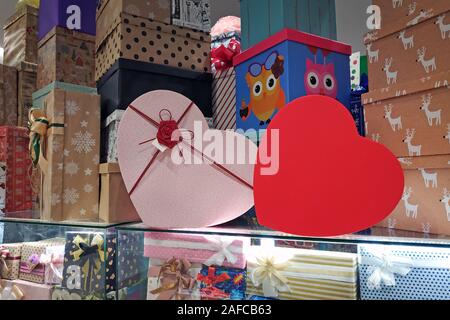 Multicolored gift boxes with bows in the mall. Paper boxes for decorating Christmas presents. Two heart-shaped boxes for Valentine's Day. Stock Photo