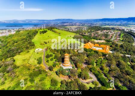 Distant Pacific ocean coast and Illawarra lake around green cultivated park of Nantien buddhist temple in Southern Hemisphere - Australian NSW. Aerial Stock Photo