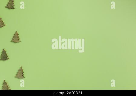 Small wooden christmas trees on green background. Christmas, winter concept. Flat lay, top view, copy space. Stock Photo