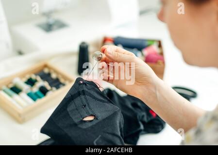 sewer sews up the hole in the pants in studio Stock Photo