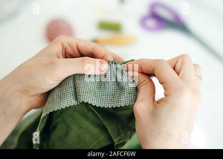 sewer sews up the hole in the pants in studio Stock Photo