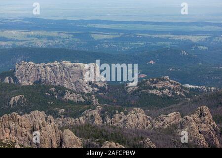 The back side of the large rock formation that is Mount Rushmore on the left with a parking area on the far right as seen from Black Elk Peak in Custe Stock Photo