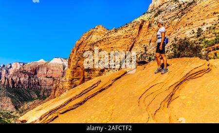 Active Senior Woman looking into Zion Canyon from the top of the Canyon Overlook Trail in Zion National Park, Utah, United States Stock Photo