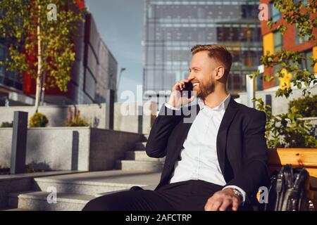 Businessman talking on the phone on the background of business building Stock Photo