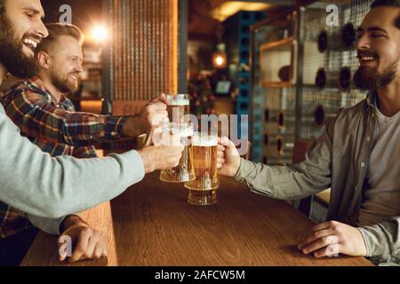 Group friends clinking glasses of beer in a bar. Stock Photo