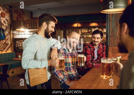 Group of male friends drink beer at a party in a bar. Stock Photo