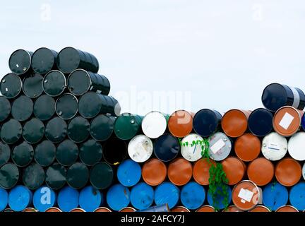 Old chemical barrels. Blue, orange, and black oil drum. Steel oil tank. Toxic waste warehouse. Hazard chemical barrel. Industrial waste in metal drum. Stock Photo