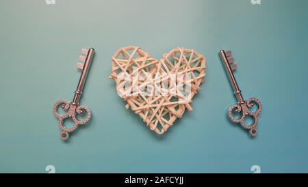 A pair of matching keys on two sides of a woven heart. Stock Photo