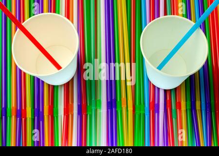 Drinking straws. Abstract background with many multi colored plastic tubules for juice or cocktail, single-use disposable. And two empty white paper c Stock Photo