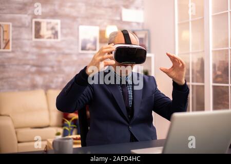 Elderly man experiencing new virtual reality technology for the first time in his home Stock Photo