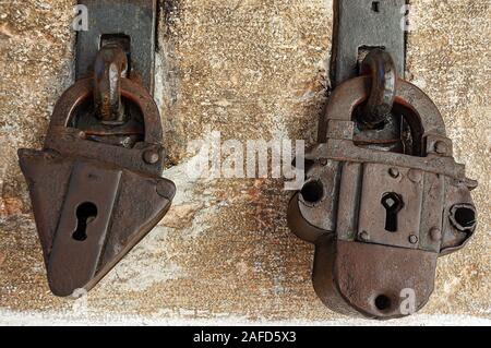 Close-up of two ancient rusty padlocks with keyhole with a stone wall on background Stock Photo