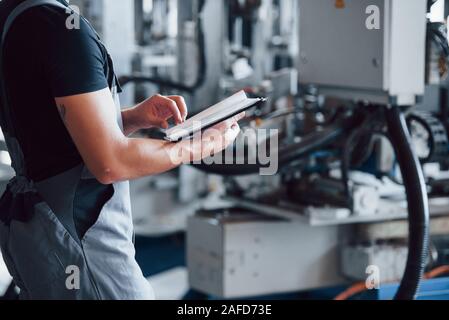 Turns the page of notepad. Industrial worker indoors in factory. Young technician Stock Photo