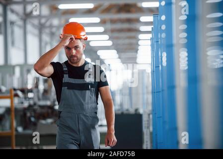 Taking off hard hat. After the work. Industrial worker indoors in factory. Young technician Stock Photo