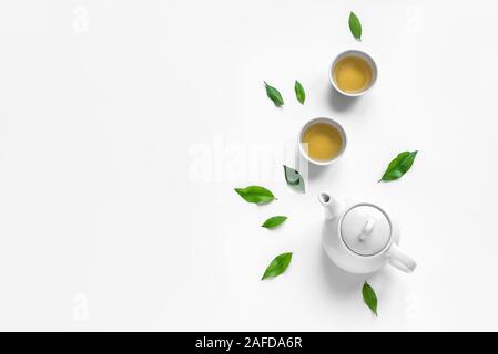 Green Tea Composition with tea leaves on white background. Chinese traditional tea set, tea culture concept, top view, copy space. Stock Photo